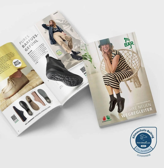 Two open fashion catalogs from BÄR-Schuhe showing a woman smiling on a swing and the latest barefoot shoe models.