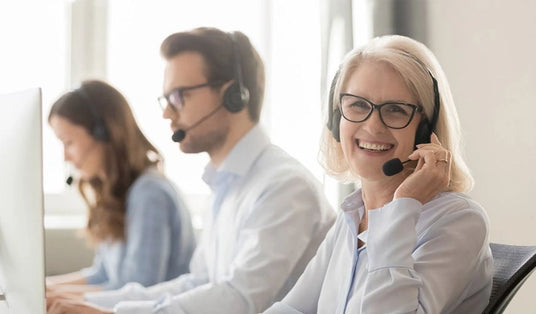 Three people in customer support with headsets working at computers