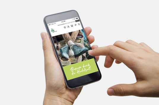 Hand holding smartphone with online shoe shop on screen