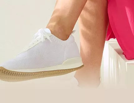 A person sits on stairs wearing white shoes next to a leaf. Text: Professional shoes for hospitals, clinics, and nursing.