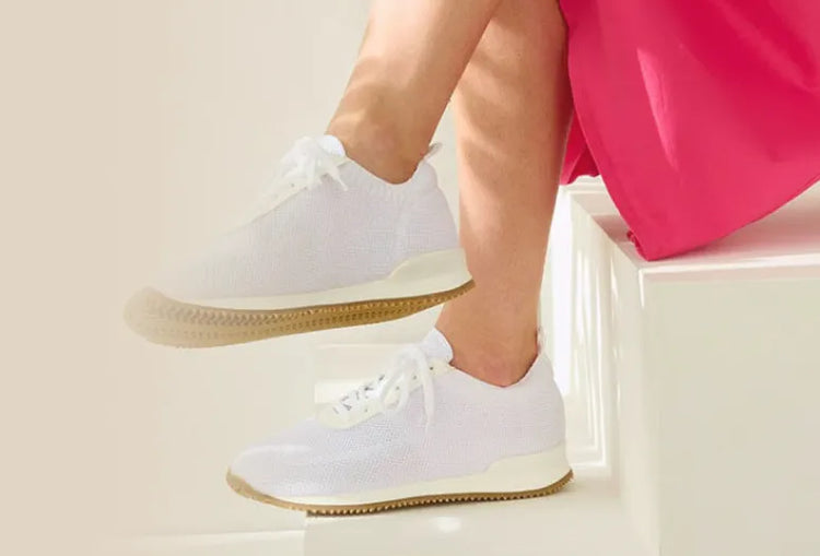 A person sits on stairs wearing white shoes next to a leaf. Text: Professional shoes for hospitals, clinics, and nursing.