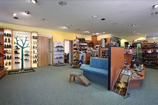 Ein Schuhgeschäft mit Regalen voller Schuhe, einem blauen Sofa und Spiegeln zur Anprobe