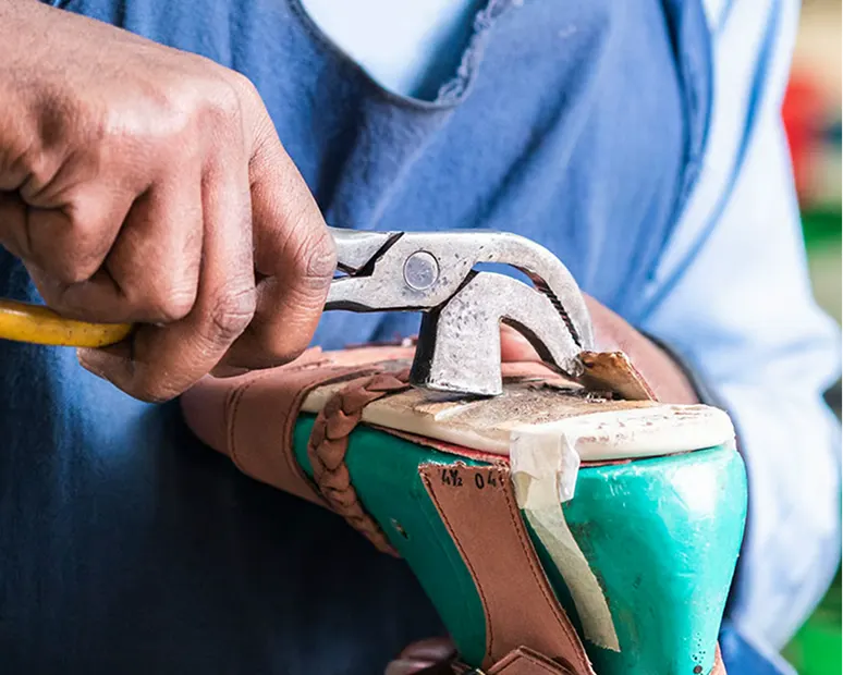 Gros plan d'un artisan travaillant avec un marteau sur un modèle de chaussure