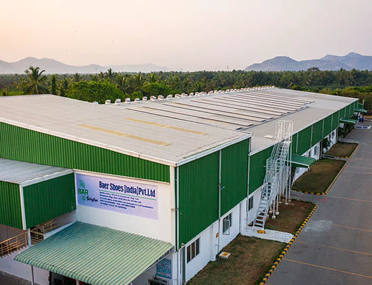 Usine verte avec des panneaux solaires sur le toit, entourée d'arbres et de montagnes en arrière-plan